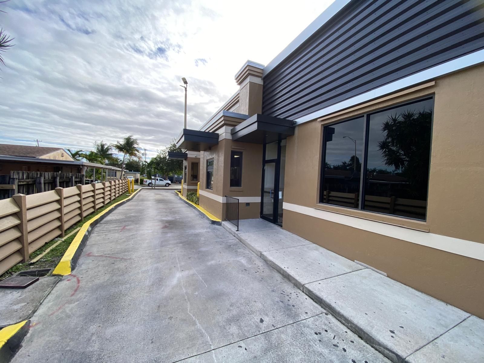 Driveway next to a beige building with dark windows under a cloudy sky.