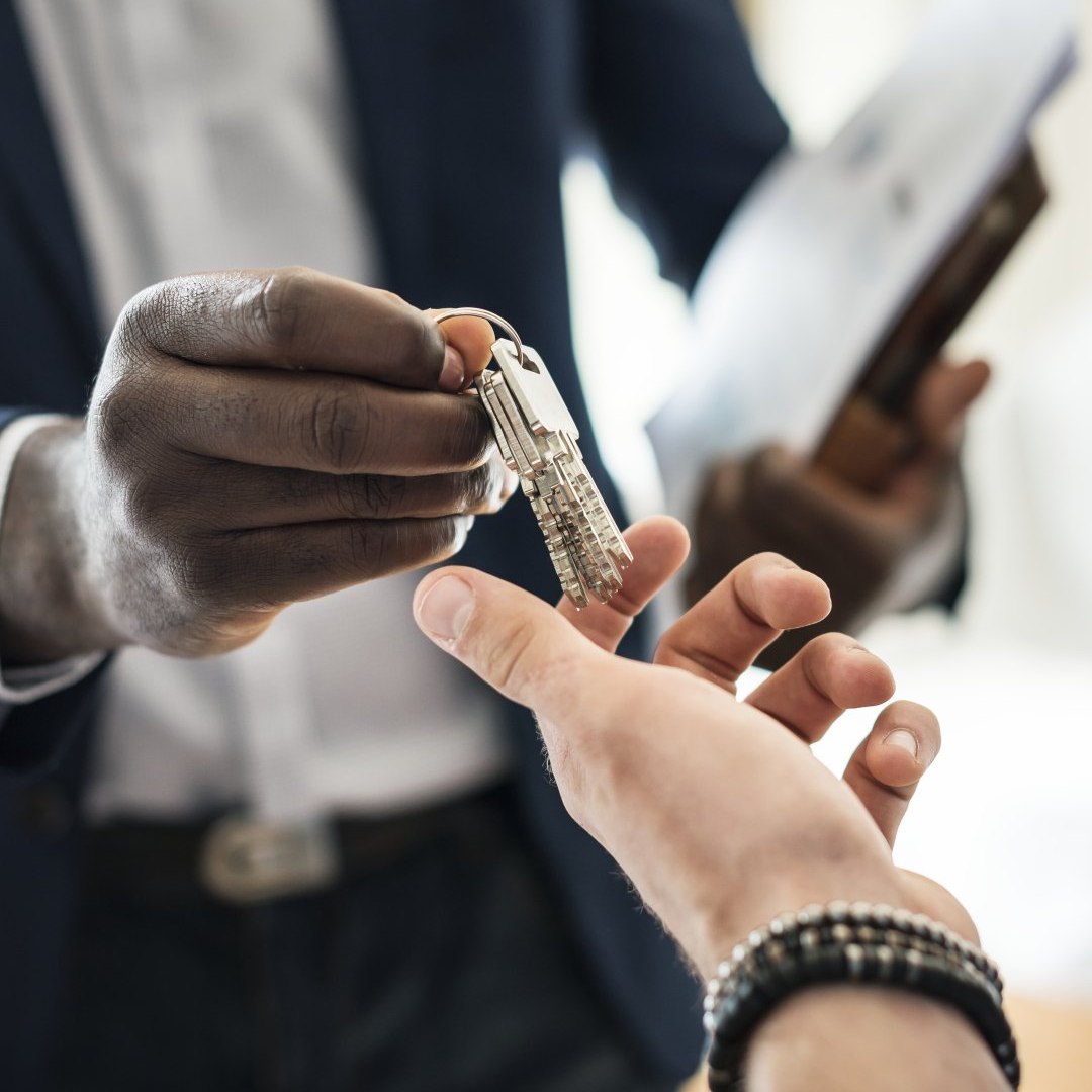 A man in a suit is handing a key to another man