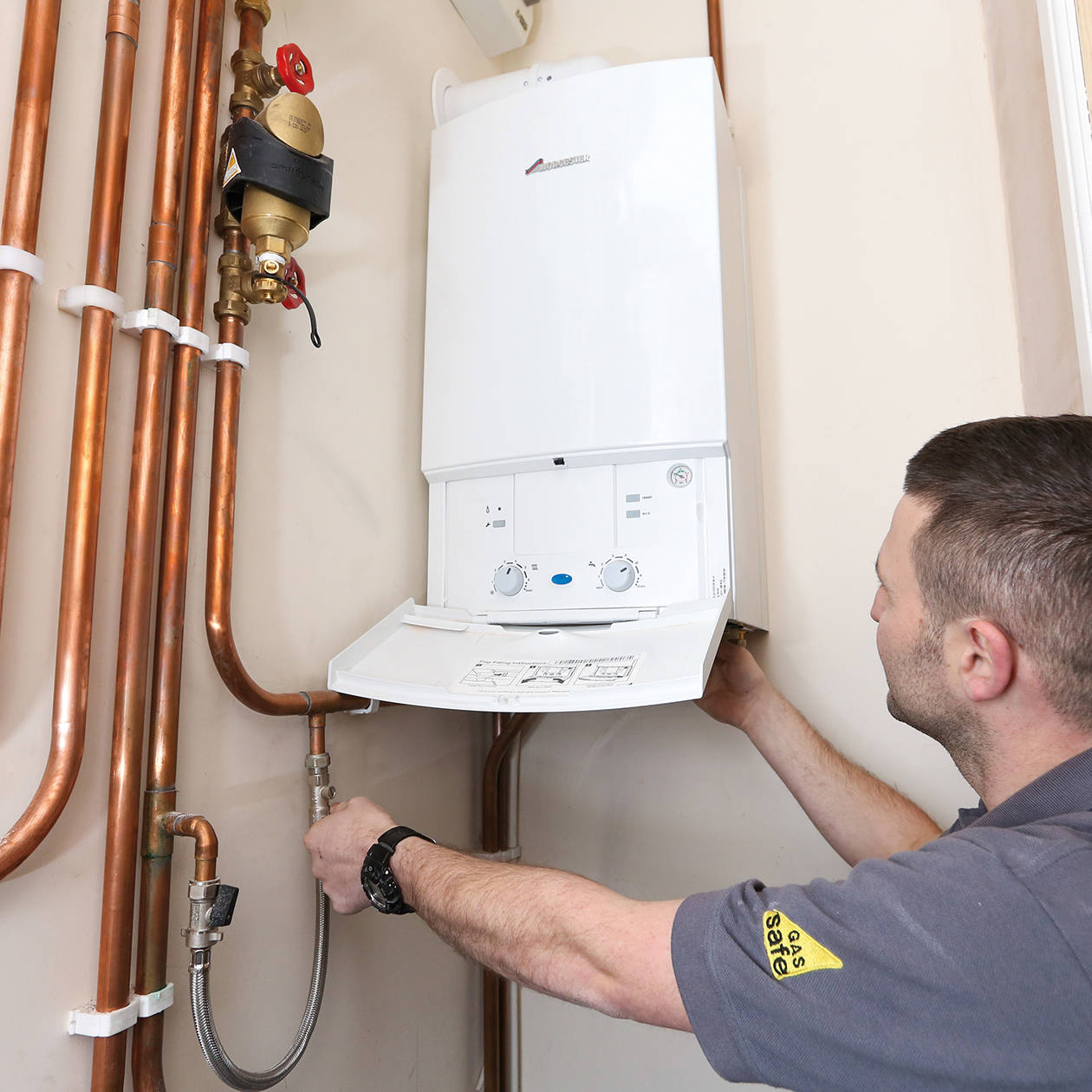 A man is working on a boiler with copper pipes