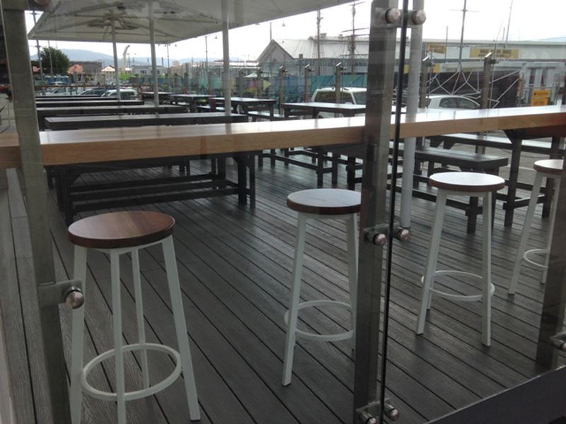 A Wooden Deck With Tables and Stools on It — B & B Timbers Ballina In West Ballina, NSW