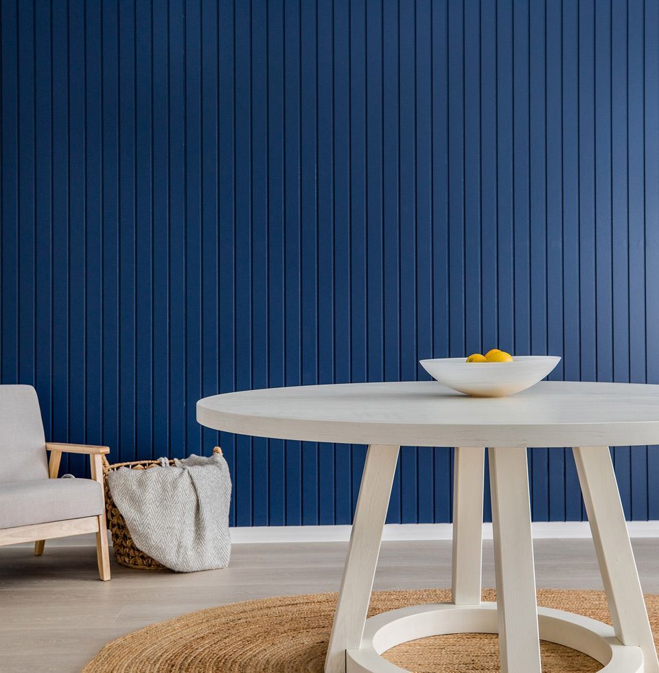 A White Table With a Bowl of Lemons on It in Front of a Blue Wall — B & B Timbers Ballina In West Ballina, NSW