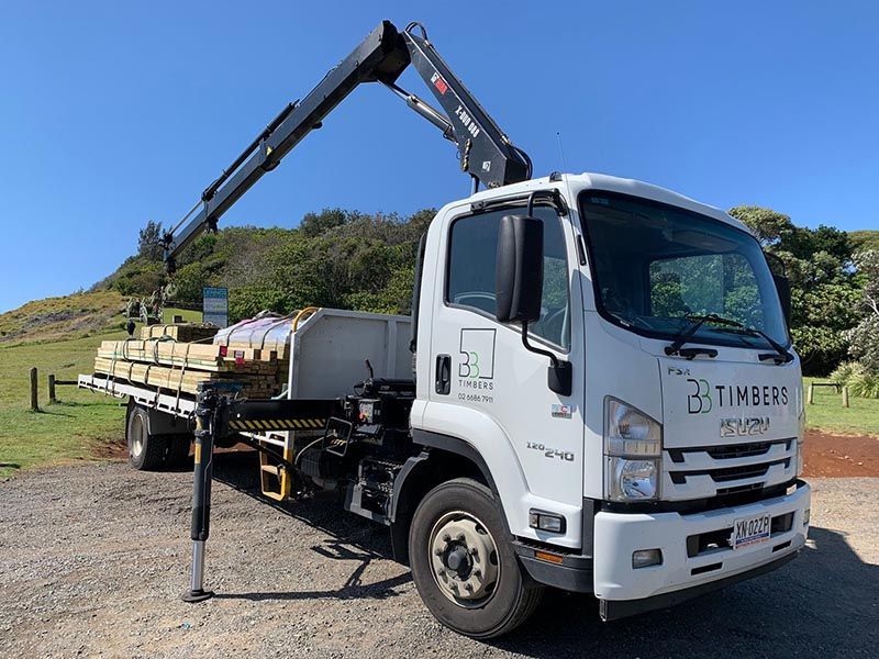 A BB Timbers Truck With a Crane on the Back is Parked in a Gravel Lot — B & B Timbers Ballina In West Ballina, NSW