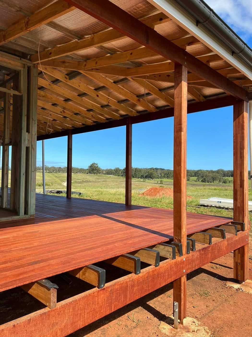 A Wooden Deck Under a Covered Porch With a Blue Sky in the Background — B & B Timbers Ballina In West Ballina, NSW
