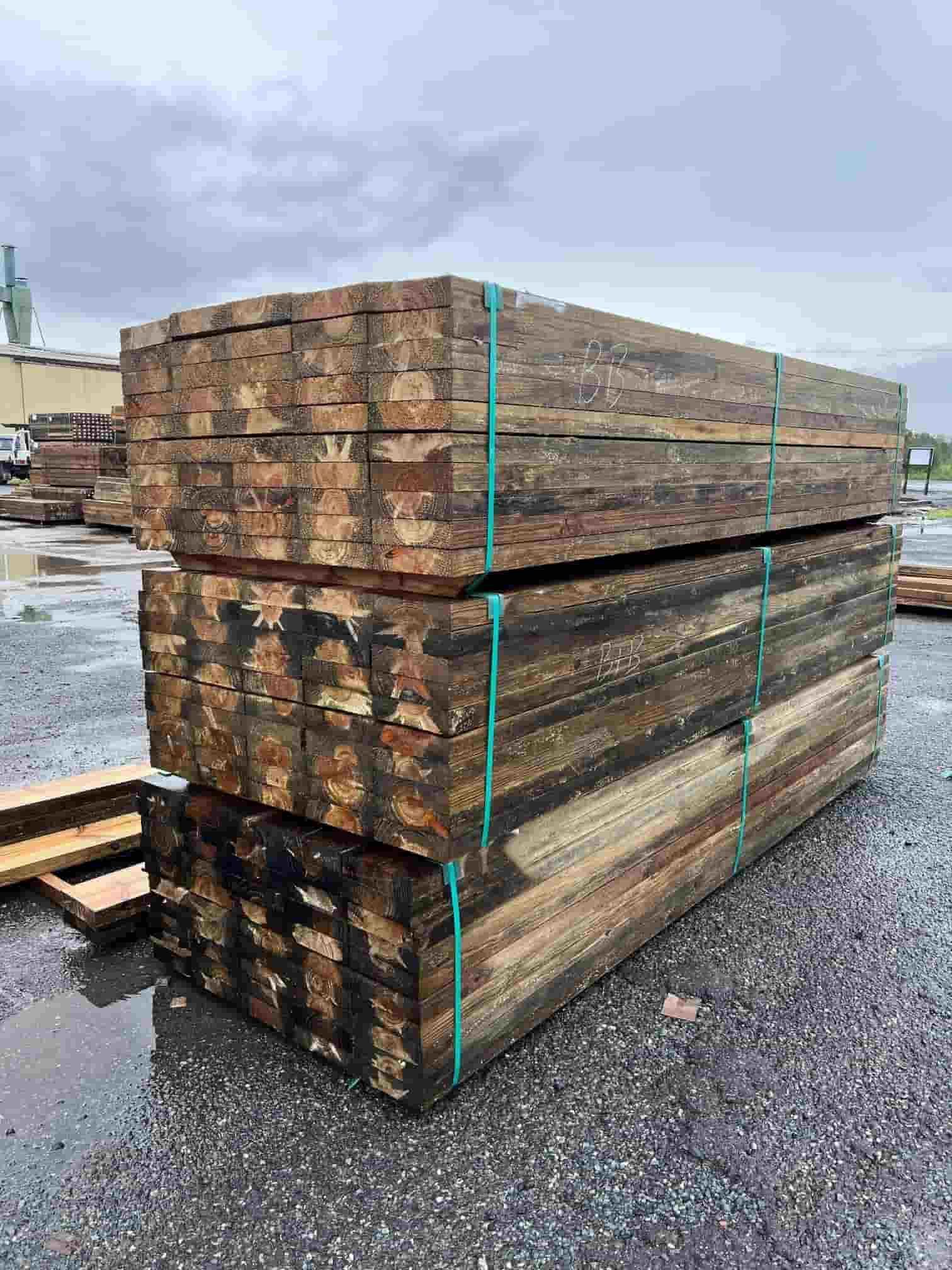 A Stack of Wooden Beams Sitting on Top of Each Other on a Gravel Road — B & B Timbers Ballina In West Ballina, NSW