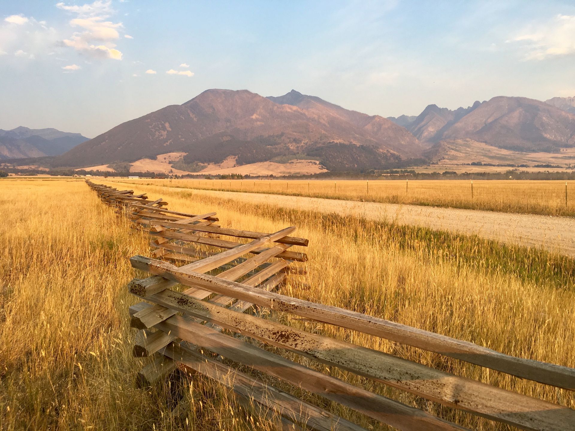 A wooden fence surrounds a field with mountains in the background.