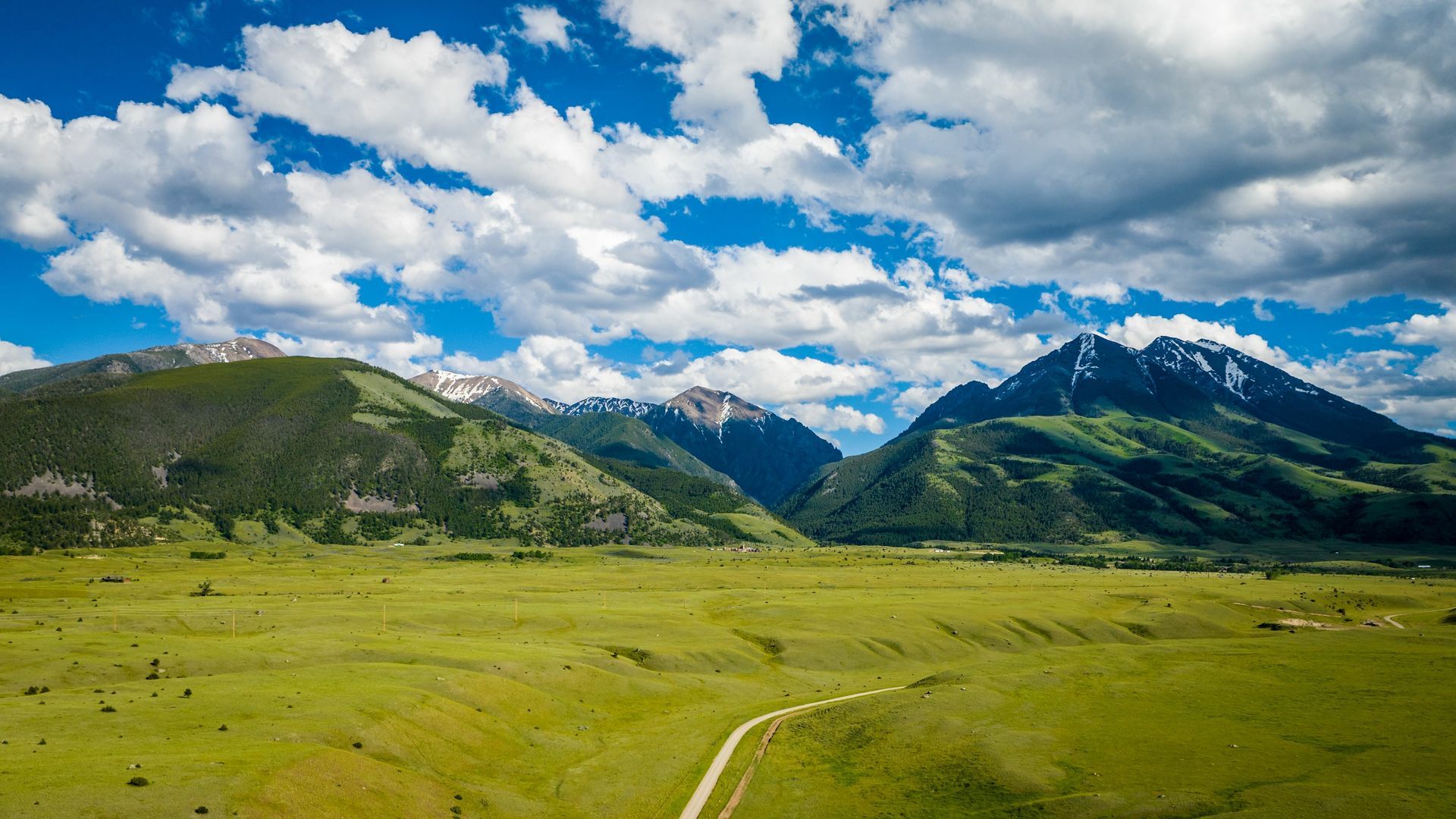 An aerial view of a river running through a lush green valley with mountains in the background.