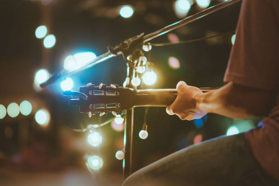 A person is playing an acoustic guitar in front of a microphone.