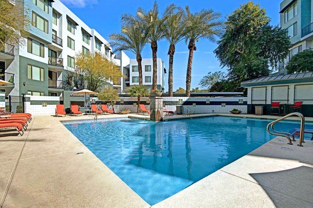 A large swimming pool surrounded by palm trees in front of a building