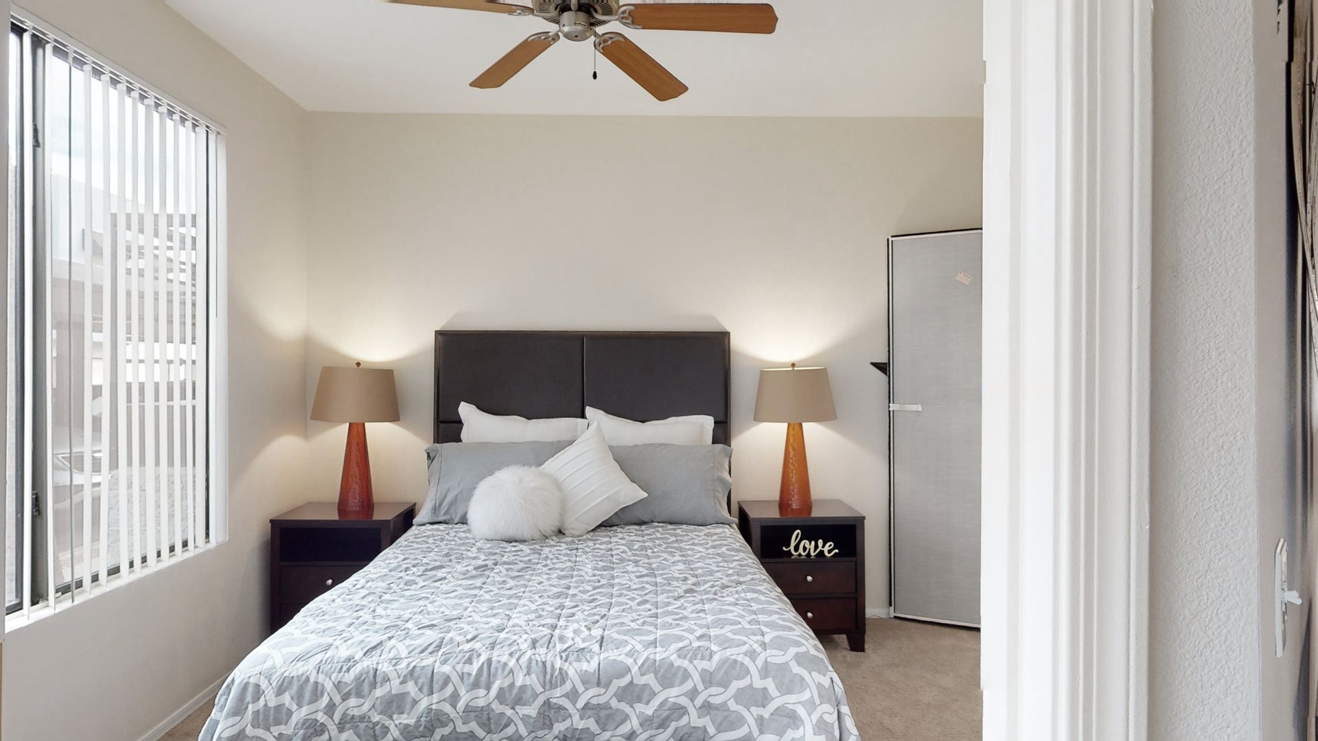 A bedroom with a bed , nightstands , lamps and a ceiling fan.