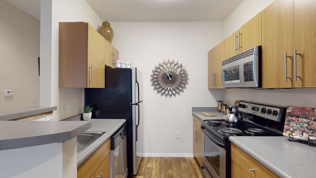 A kitchen with wooden cabinets , stainless steel appliances and a black refrigerator.