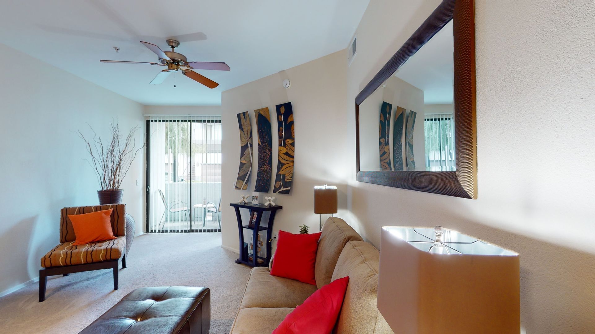 A living room with a couch , chair , mirror and ceiling fan.