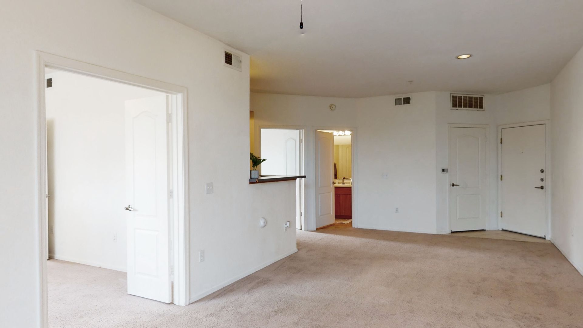 An empty room with a carpeted floor and white walls