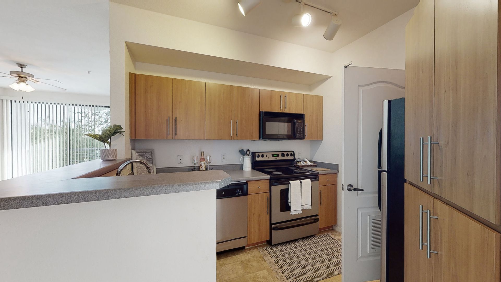 A kitchen with wooden cabinets , stainless steel appliances , a refrigerator and a microwave.