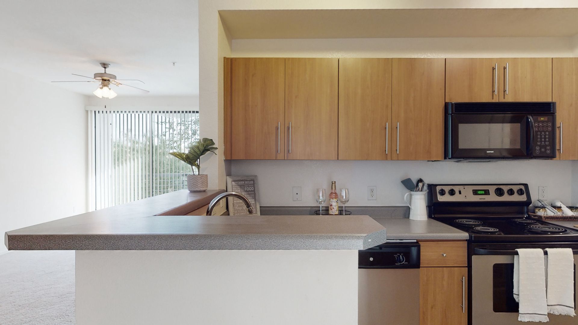 A kitchen with wooden cabinets , stainless steel appliances , a stove and a microwave.