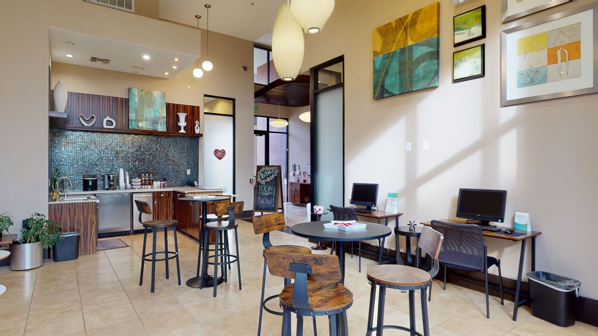 A room with tables and chairs and a kitchen in the background