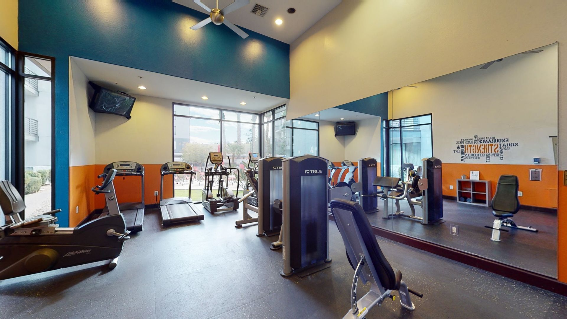 A gym with a lot of exercise equipment and a large mirror.