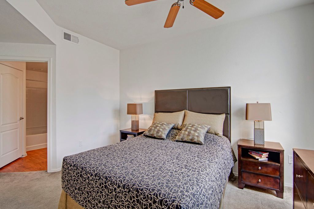 A bedroom with a large bed and a ceiling fan