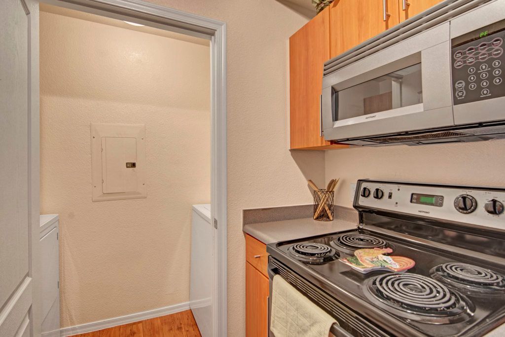 A kitchen with a stove , microwave , and cabinets.