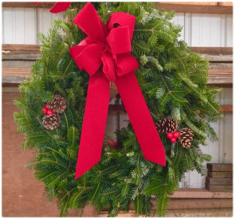 Christmas wreath with red bow and pinecones.