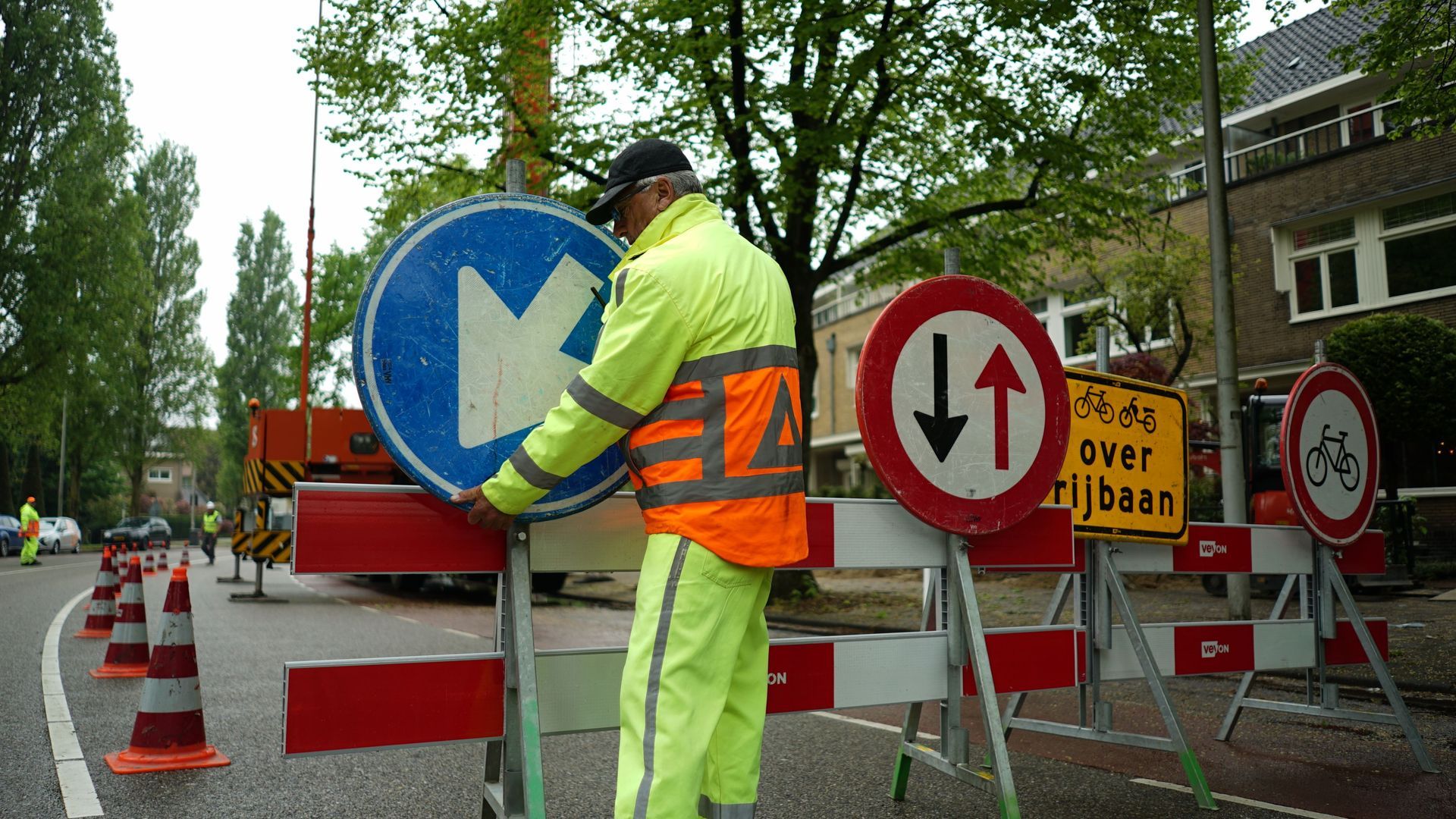 Een man in een geel vest werkt aan een verkeersbord