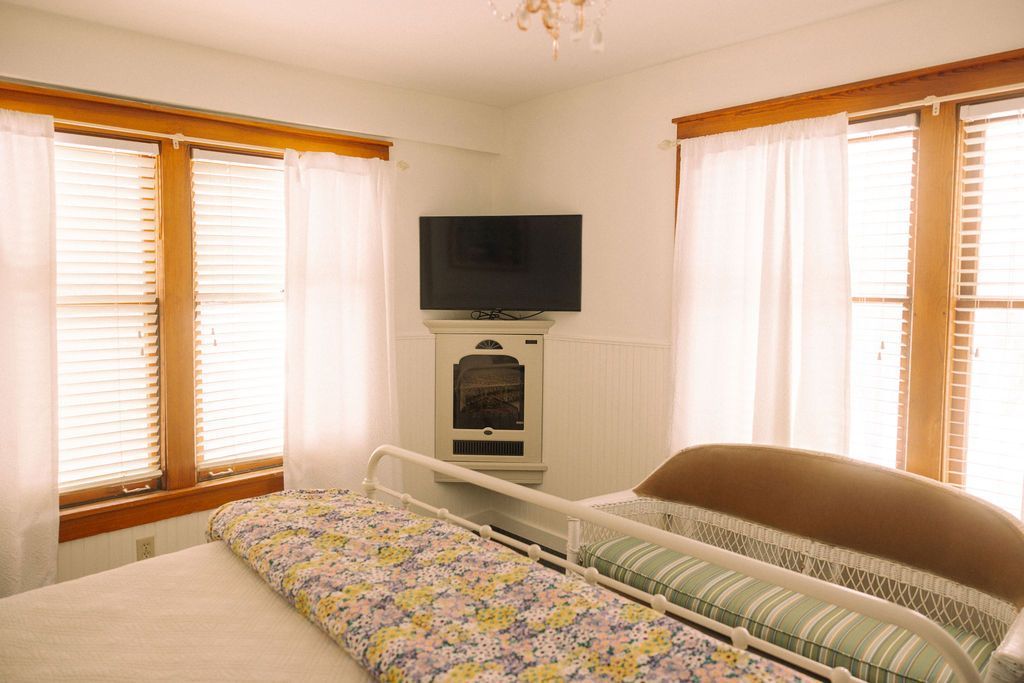 A bedroom with a bed , chairs , a television and a fireplace