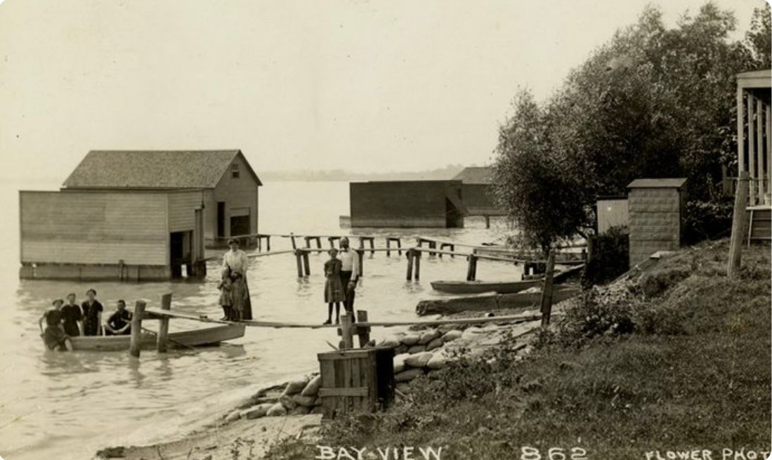 A black and white photo of a group of people in a boat in the water.