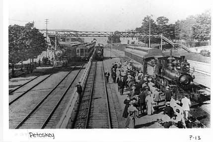 A black and white photo of people waiting for a train at a train station.