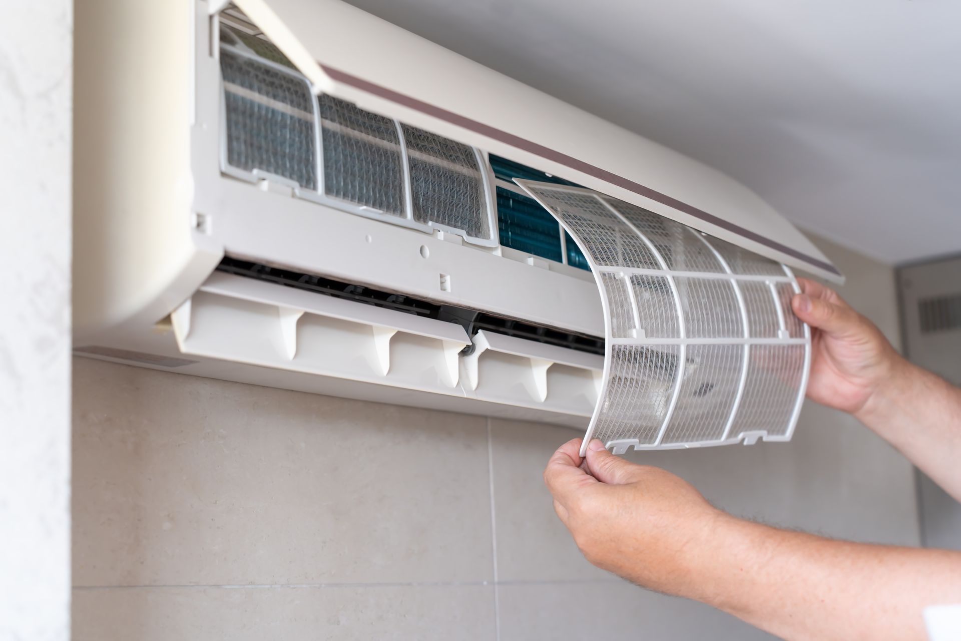 Person removing an air conditioner filter for cleaning.
