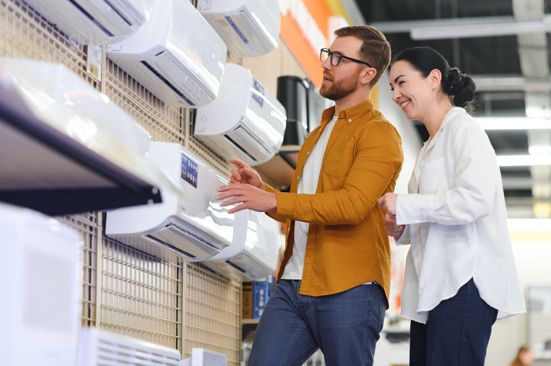 A man and a woman are looking at air conditioners in a store.