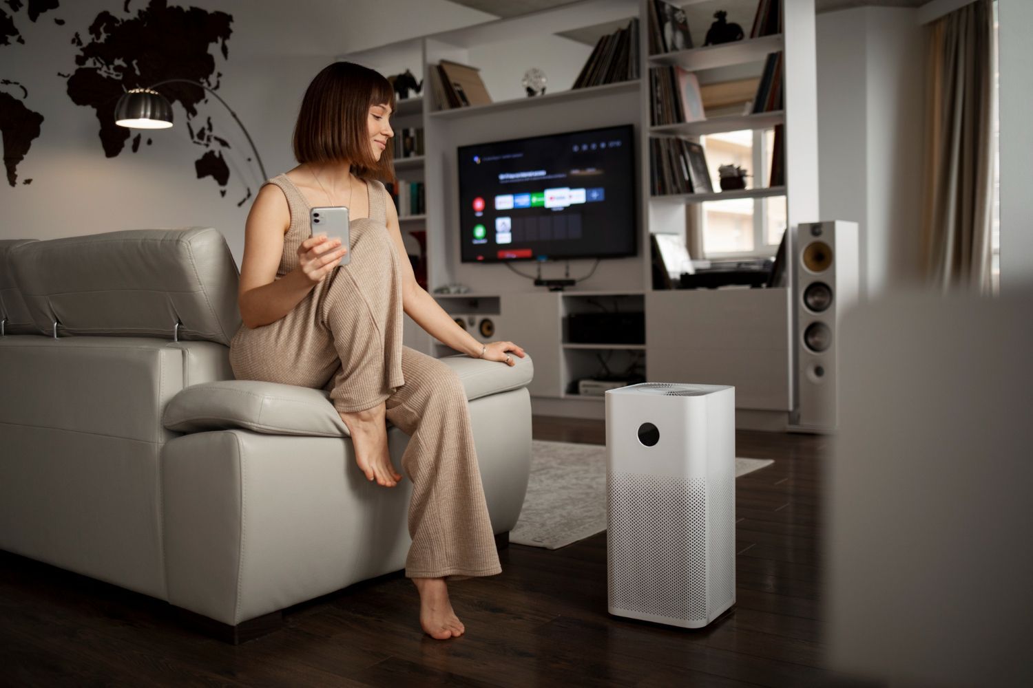A woman is sitting on a couch in a living room looking at her phone.
