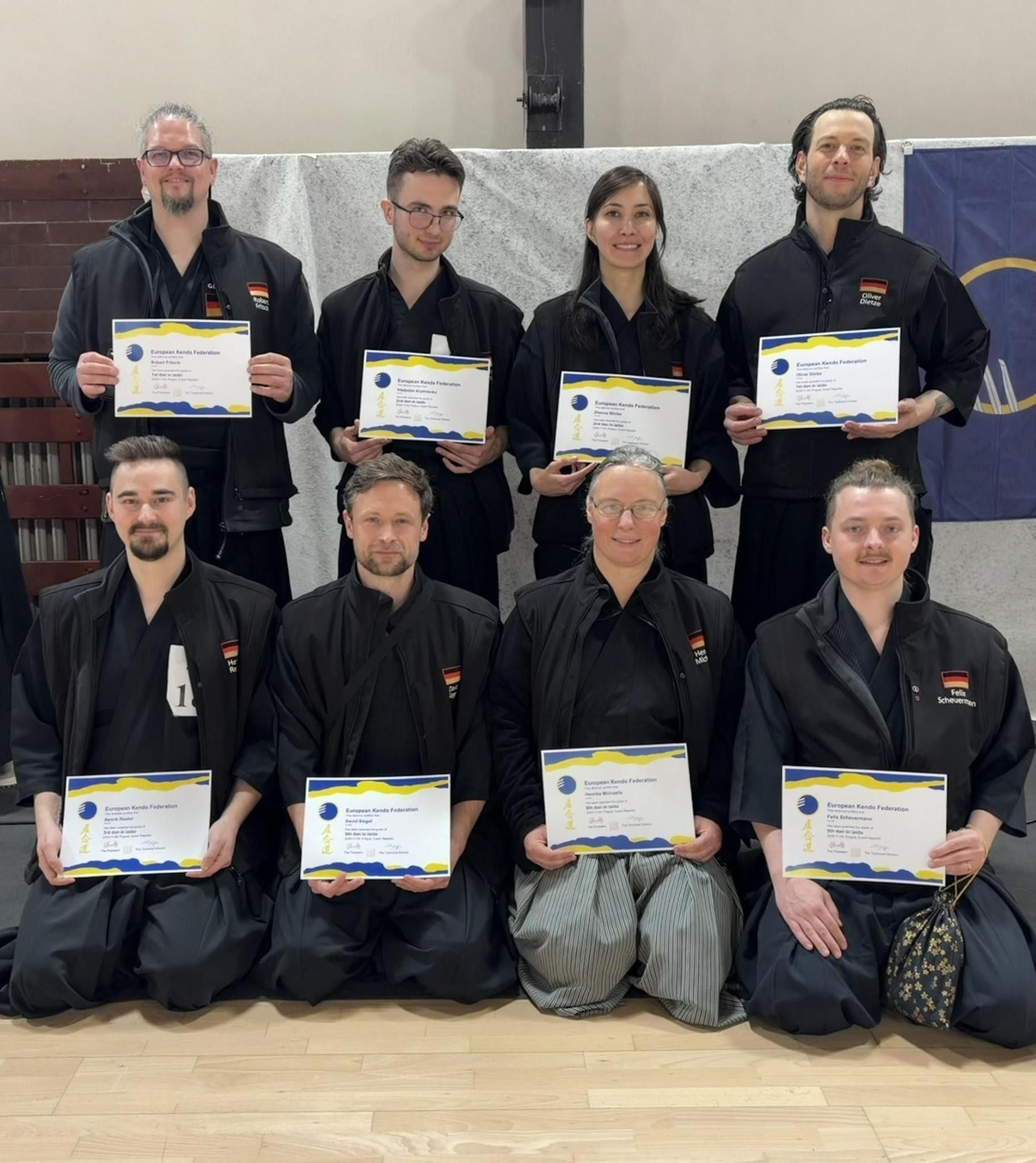 Eine Gruppe von acht Personen posiert mit Urkunden für ein Foto.