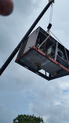 A large box is being lifted by a crane in the air.