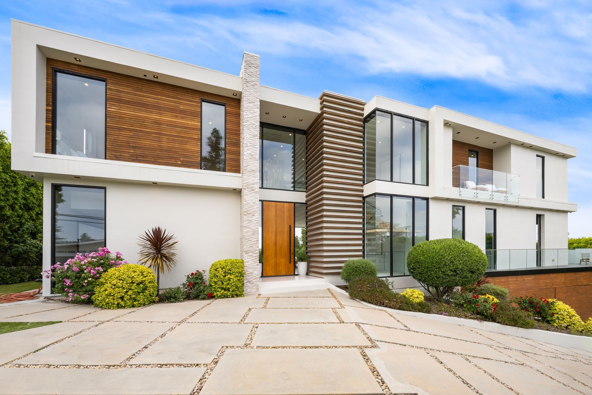 Maison moderne à deux étages avec extérieur en bois et blanc, grandes fenêtres et jardin paysager.
