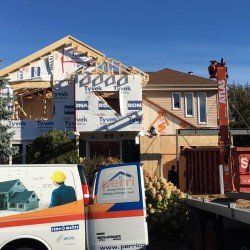 Chantier de construction avec maison partiellement construite, grue et camionnette Perri Construction.