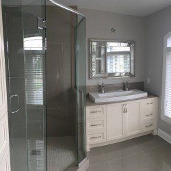 Salle de bain avec douche en verre, vanité blanche, double vasque et grand miroir.
