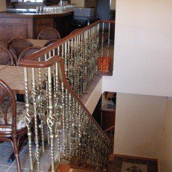 Escalier de restaurant avec rampe en laiton ornée et main courante en bois.