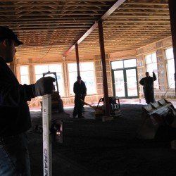 Des ouvriers du bâtiment à l'intérieur d'un bâtiment avec des poutres en bois, fixant un niveau.