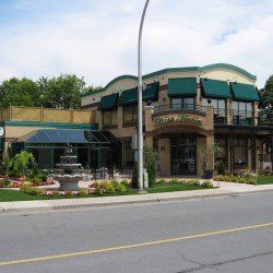 Restaurant Miss Marion, vue extérieure avec auvents verts, fontaine et aménagement paysager.