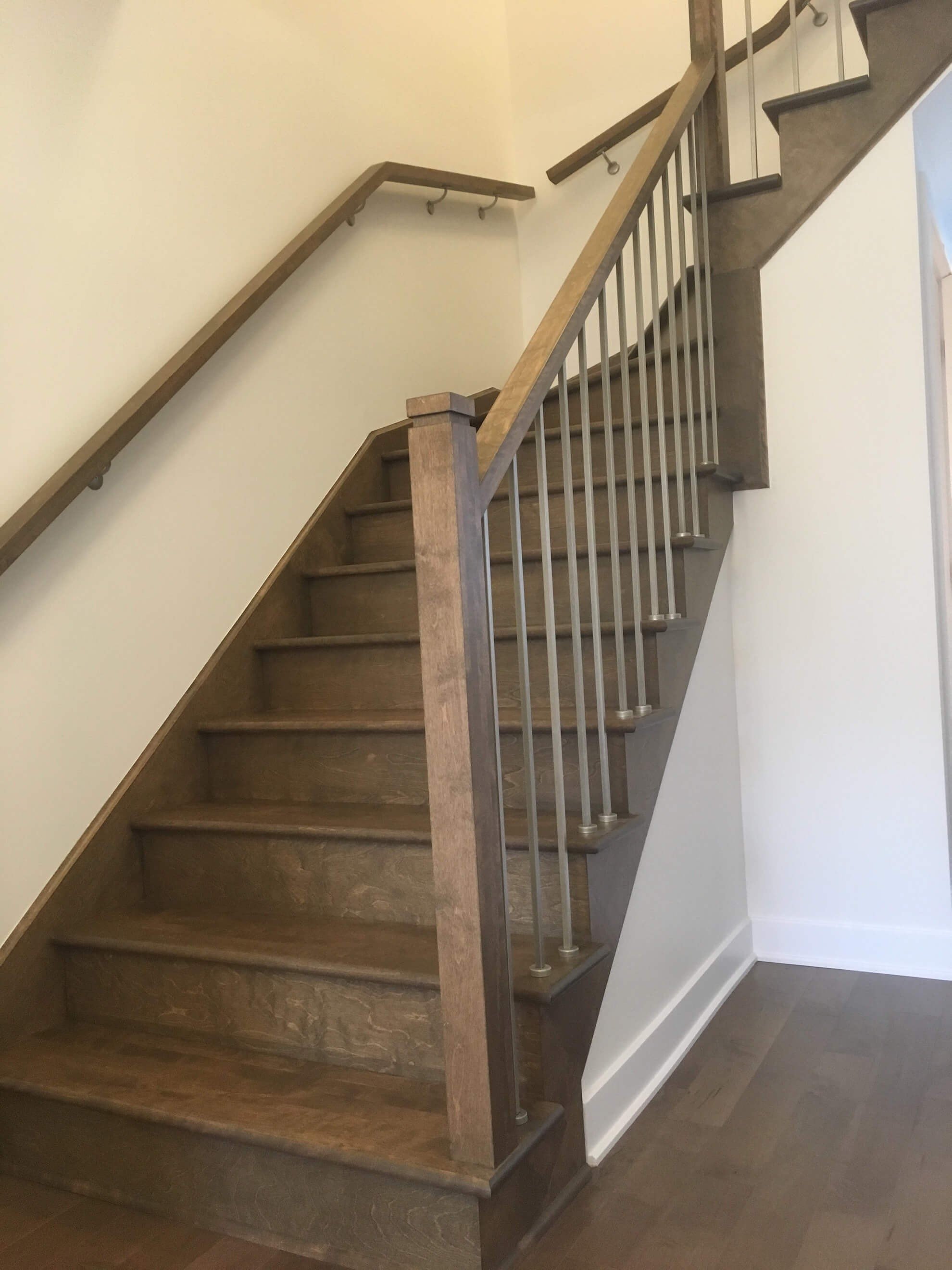 Escalier en bois avec rampe en bois et métal; marches marron, murs de couleur claire.
