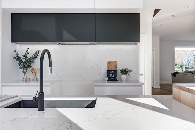 Cuisine moderne avec robinet noir, comptoirs blancs et armoires grises.