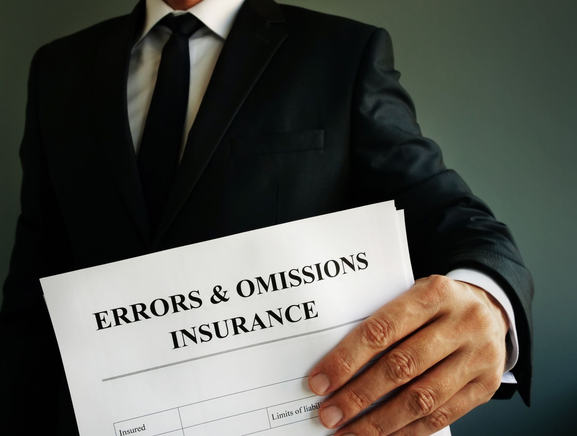 A businessman in a suit and tie holding an errors and omissions insurance document