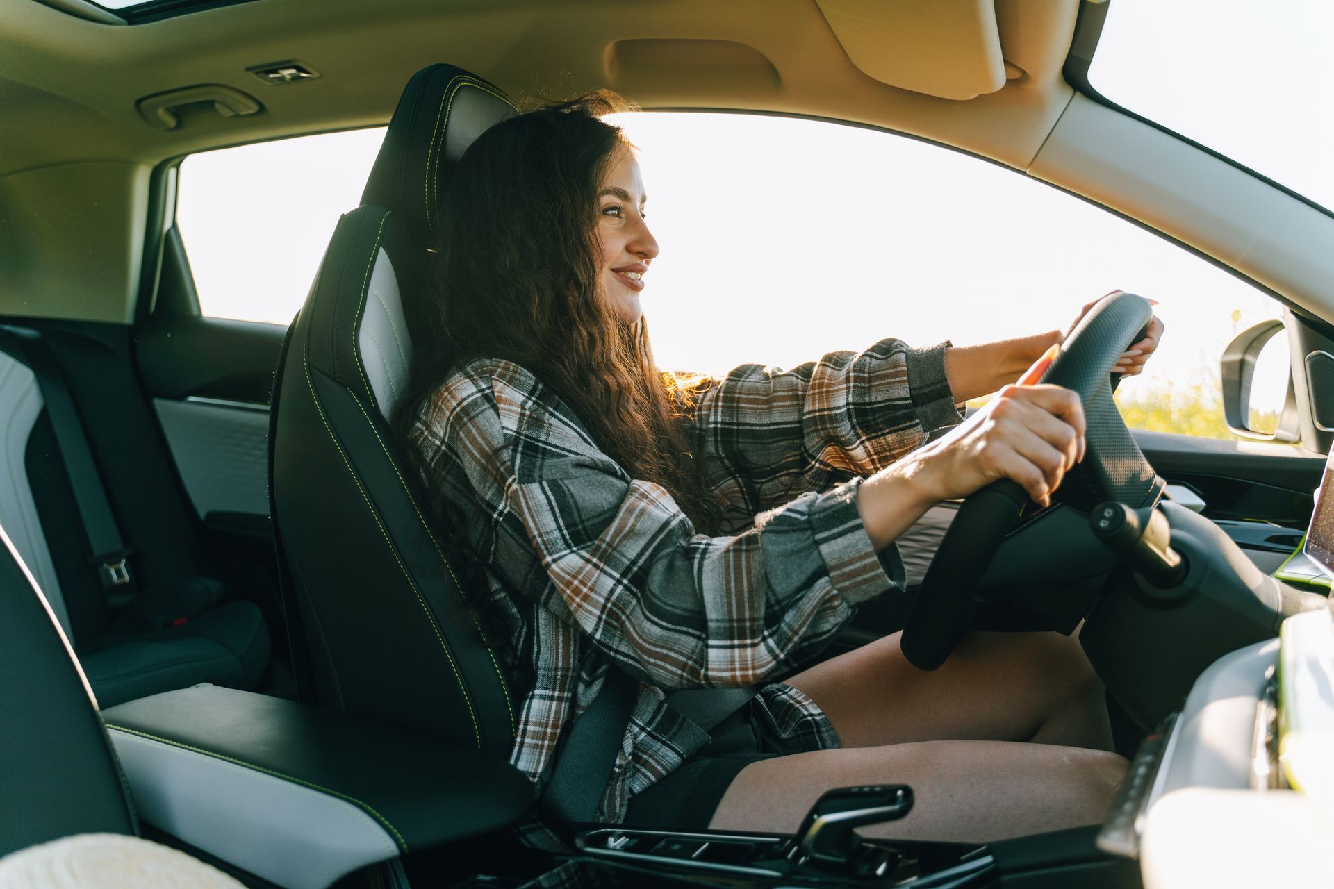 A woman confidently drives a car on a sunny day.