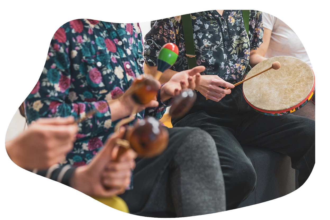 Persone che suonano insieme strumenti a percussione, tra cui maracas e un tamburo a mano.
