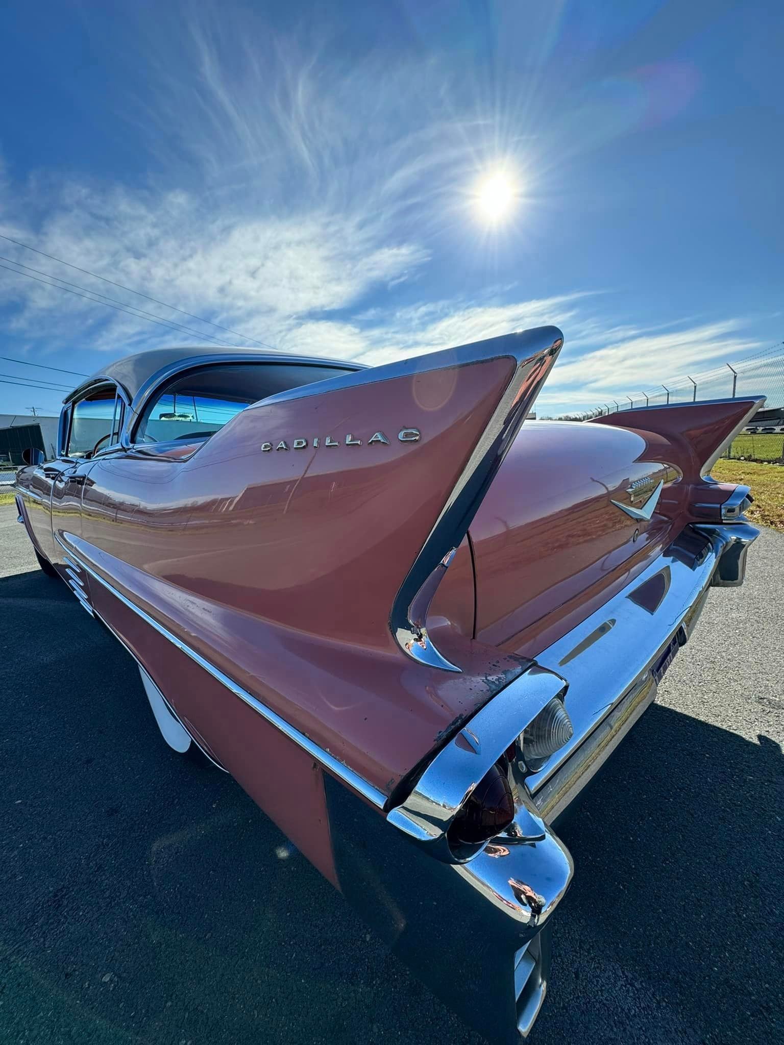 A red cadillac is parked on the side of the road.