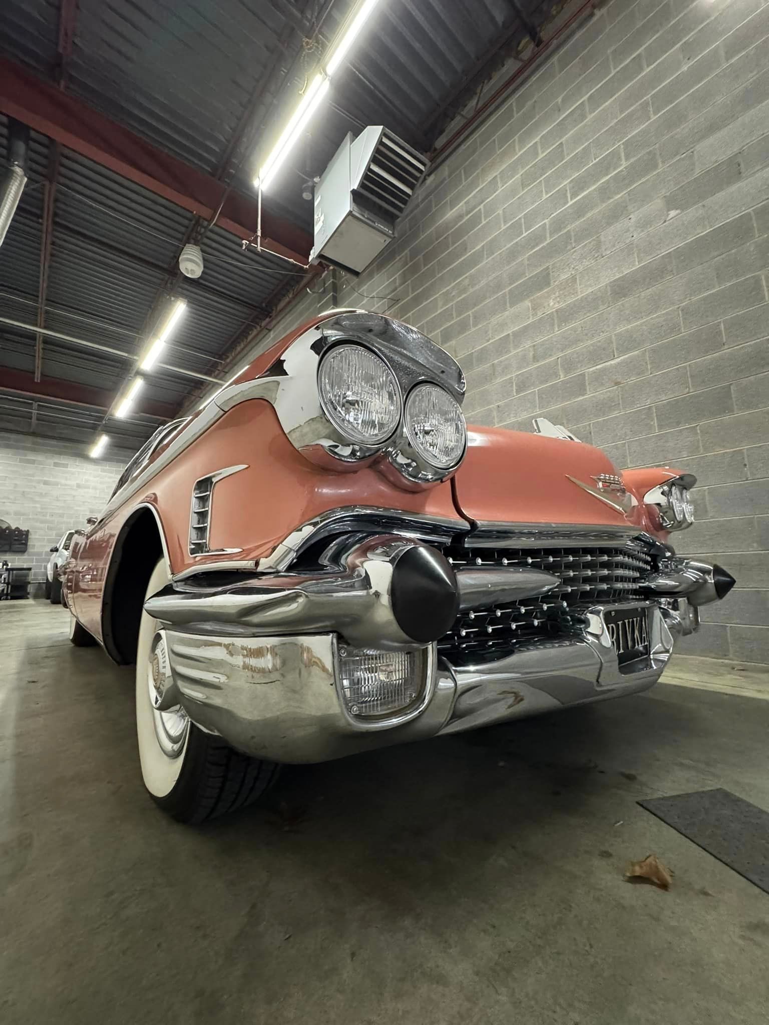 A red cadillac is parked in a garage next to a brick wall.