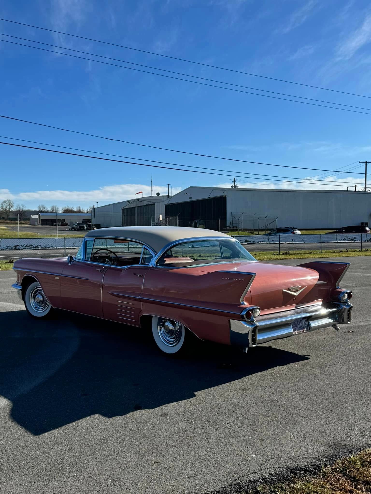 A pink cadillac is parked in a parking lot.