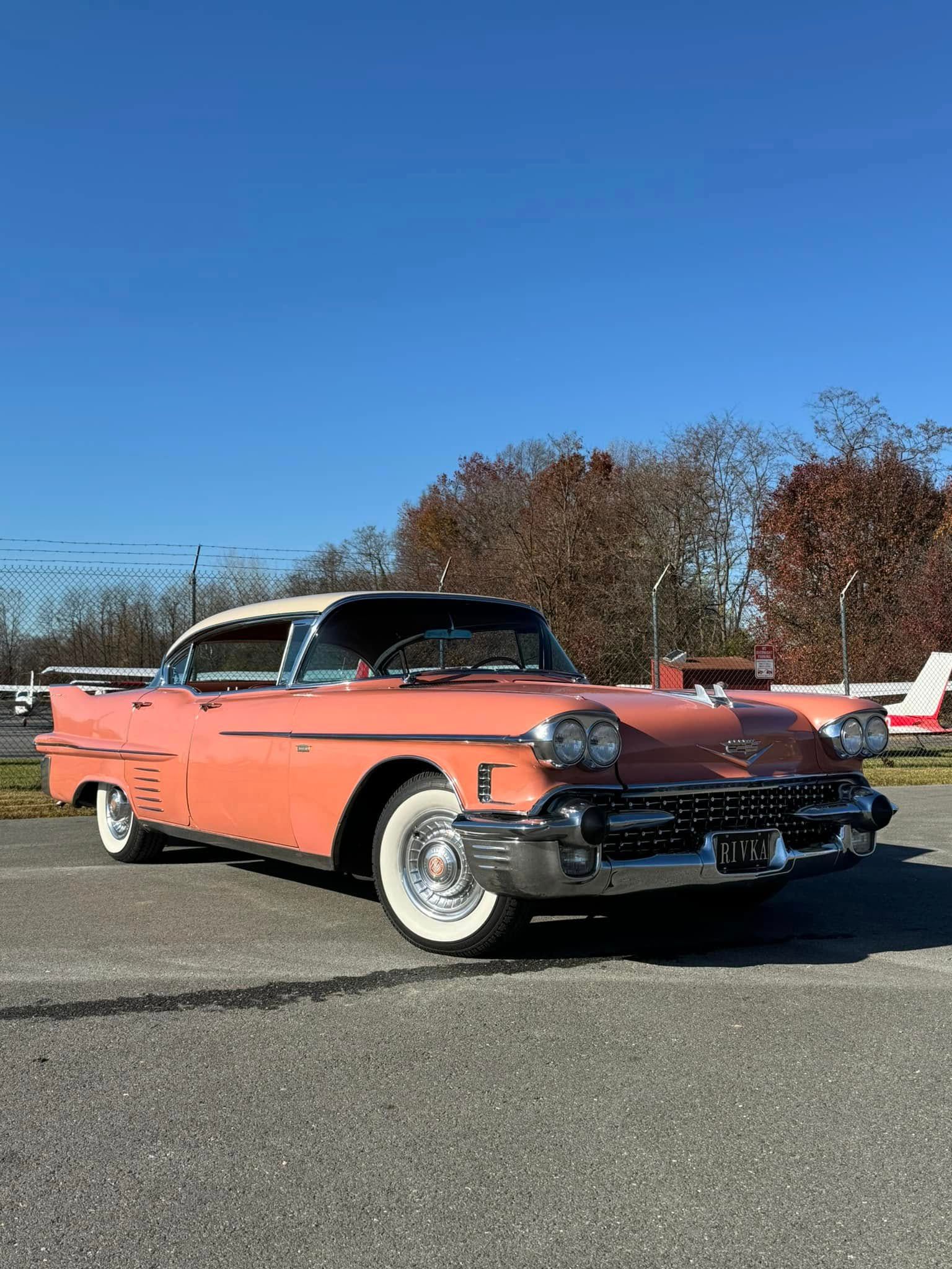 A pink cadillac is parked in a parking lot.