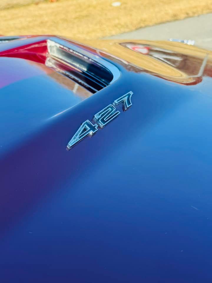 A close up of the hood of a blue car with the letters 427 on it.