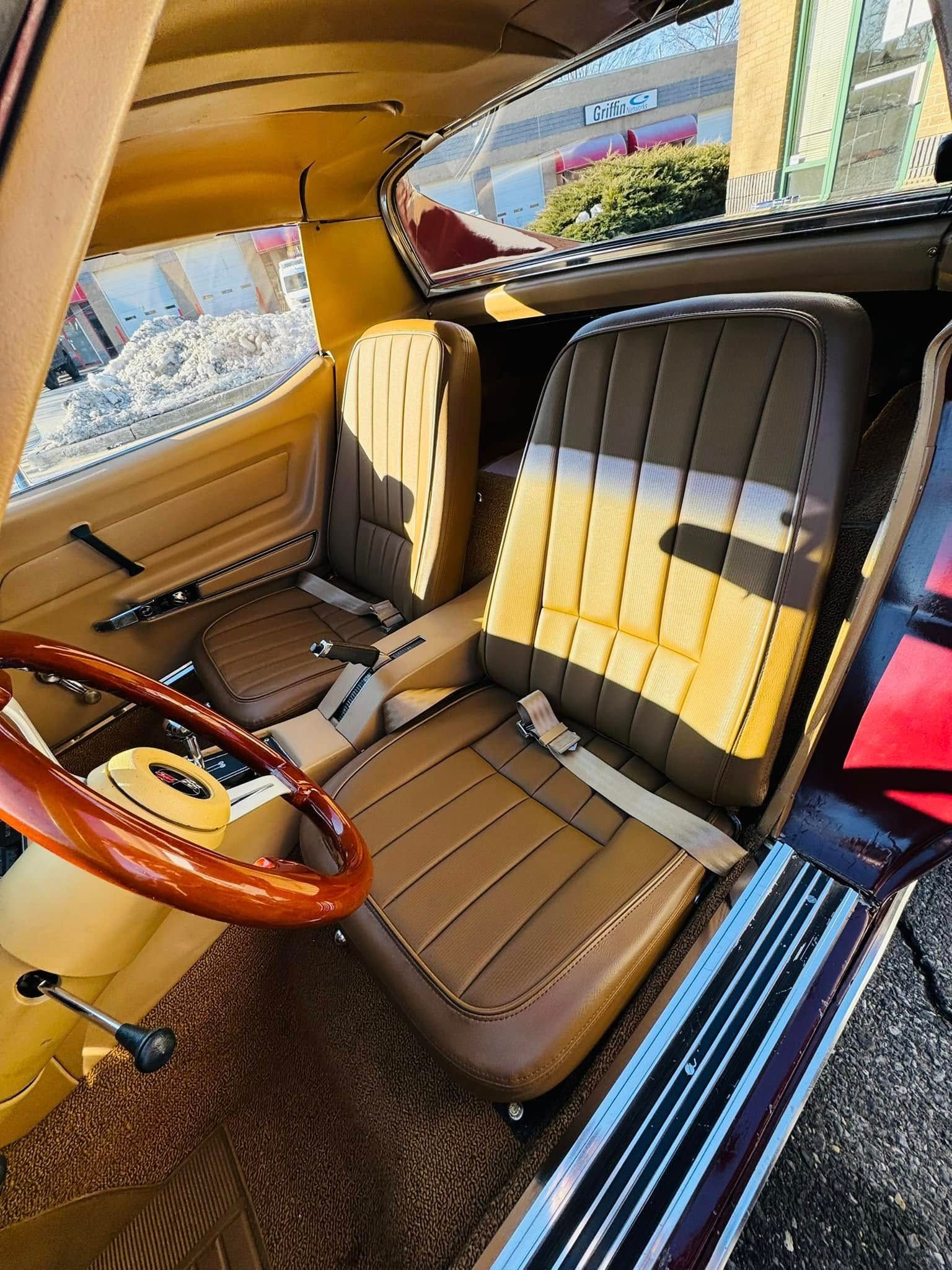 The interior of a yellow car with brown seats and a wooden steering wheel.