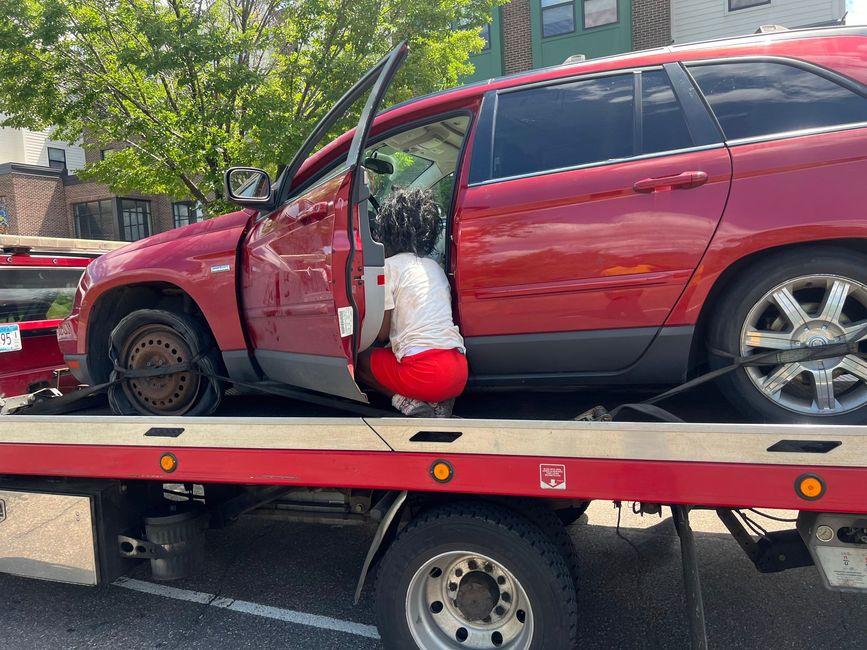 Red SUV on a tow truck with the driver’s door open and a Santa decoration hanging inside